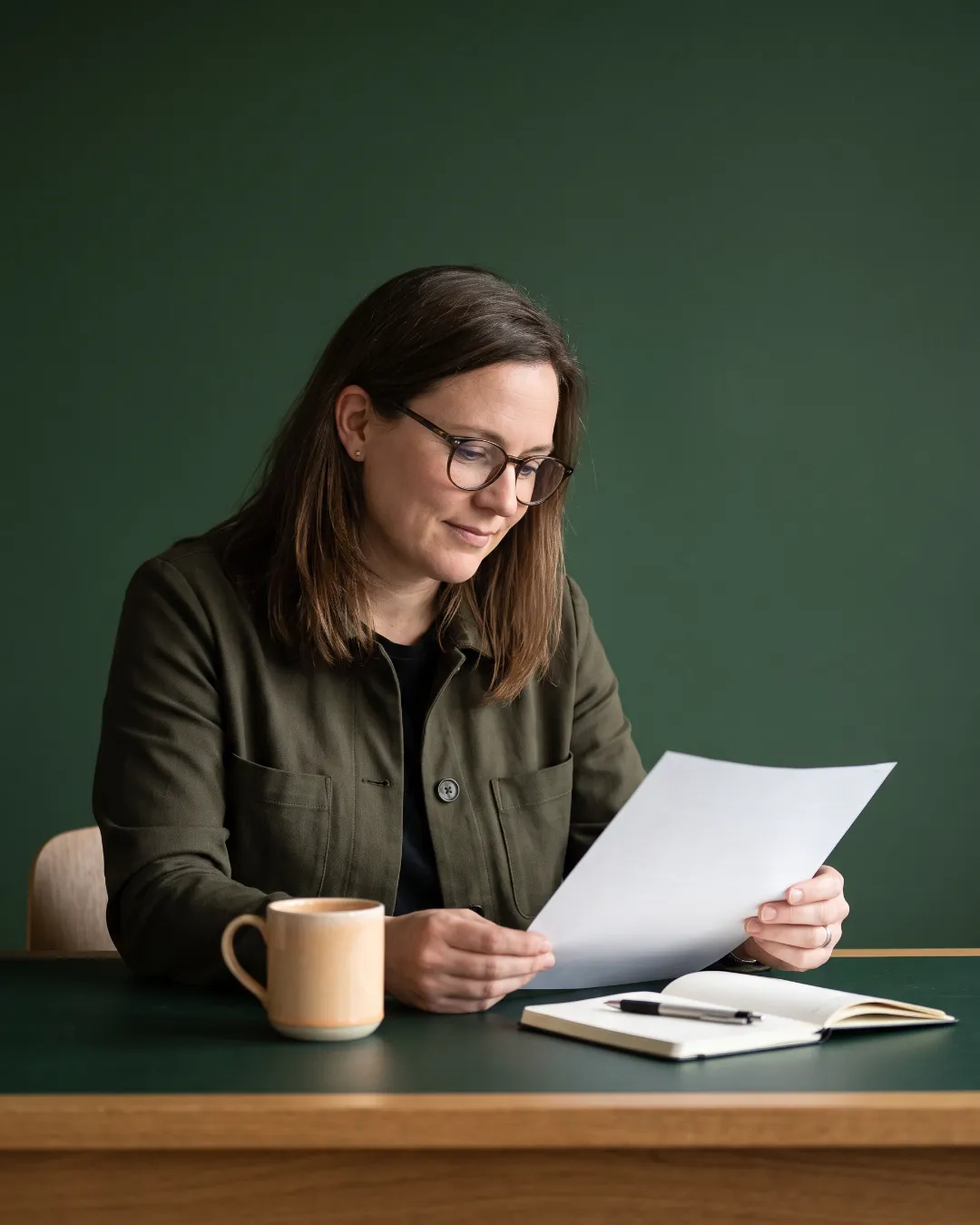 A professional reviewing a document at her desk